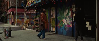 Movie still from “Across the Universe” (2007), directed by Julie Taymor – A man walking down the street in front of a building; Wide shot, Low angle