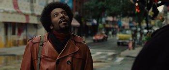 Movie still from “Across the Universe” (2007), directed by Julie Taymor – A man standing on the side of the street looking up; Close Up shot, Low angle