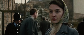 Movie still from “Across the Universe” (2007), directed by Julie Taymor – A woman standing in front of a group of people; Close Up shot, Over the shoulder angle