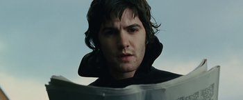 Movie still from “Across the Universe” (2007), directed by Julie Taymor – A person looking at a newspaper; Close Up shot, Over the shoulder angle