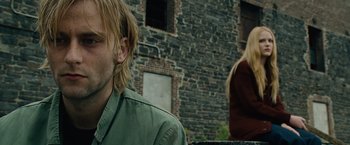 Movie still from “Across the Universe” (2007), directed by Julie Taymor – A man and a woman in front of a brick building; Close Up shot, Over the shoulder angle