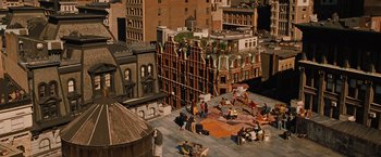 Movie still from “Across the Universe” (2007), directed by Julie Taymor – A group of people sitting on top of a building; Extreme Wide shot, Overhead angle