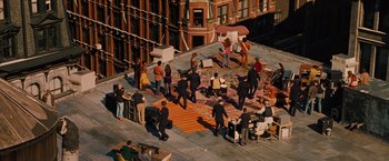 Movie still from “Across the Universe” (2007), directed by Julie Taymor – A group of people standing on top of a building; Extreme Wide shot, High angle