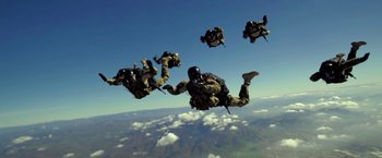 Movie still from “Act of Valor” (2012), directed by Scott Waugh – A group of parachutists in the air with their parachuting equipment; Wide shot, Low angle