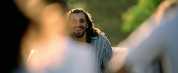 Movie still from “Act of Valor” (2012), directed by Scott Waugh – A man with long hair is smiling for the camera; Close Up shot, Over the shoulder angle