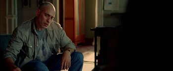 Movie still from “Act of Valor” (2012), directed by Scott Waugh – A man sitting on the ground in a room; Close Up shot, Over the shoulder angle