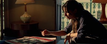Movie still from “Act of Valor” (2012), directed by Scott Waugh – A woman playing a game of dominoes in a room; Medium shot, Over the shoulder angle