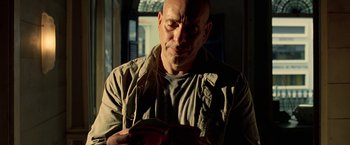 Movie still from “Act of Valor” (2012), directed by Scott Waugh – A bald man is looking down at a book in his hands; Close Up shot, Low angle