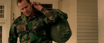Movie still from “Act of Valor” (2012), directed by Scott Waugh – A man in military fatigues holding onto a bag; Medium shot, Over the shoulder angle