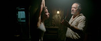 Movie still from “Act of Valor” (2012), directed by Scott Waugh – A woman standing next to a man holding a cell phone up to her head; Medium shot, Low angle