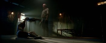Movie still from “Act of Valor” (2012), directed by Scott Waugh – An old man standing in a dimly - lit room; Wide shot, Low angle