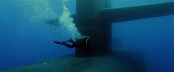 Movie still from “Act of Valor” (2012), directed by Scott Waugh – A person in the water near a metal structure; Wide shot, Overhead angle