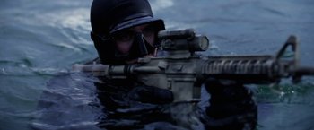 Movie still from “Act of Valor” (2012), directed by Scott Waugh – A man in a helmet and goggles is holding a rifle in the water; Close Up shot, Over the shoulder angle
