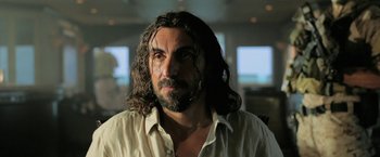 Movie still from “Act of Valor” (2012), directed by Scott Waugh – A man with long hair and a goatee stares into the camera; Close Up shot, Low angle