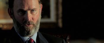 Movie still from “Act of Valor” (2012), directed by Scott Waugh – A person wearing a suit and tie; Close Up shot, Over the shoulder angle