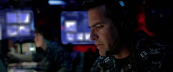 Movie still from “Act of Valor” (2012), directed by Scott Waugh – A man with a headset on looking into the distance; Close Up shot, Over the shoulder angle