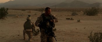 Movie still from “Act of Valor” (2012), directed by Scott Waugh – A man in a military uniform walking through the desert; Medium shot, Over the shoulder angle