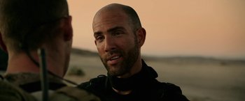 Movie still from “Act of Valor” (2012), directed by Scott Waugh – A man with a bald head is looking at the camera; Close Up shot, Over the shoulder angle