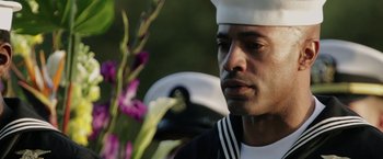 Movie still from “Act of Valor” (2012), directed by Scott Waugh – A man in a sailor's uniform looking at a flower; Close Up shot, Over the shoulder angle