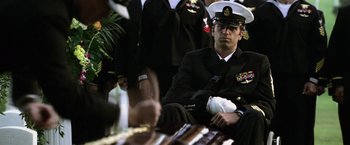 Movie still from “Act of Valor” (2012), directed by Scott Waugh – A man in a military uniform sitting in front of a group of people; Medium shot, Over the shoulder angle