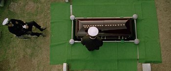Movie still from “Act of Valor” (2012), directed by Scott Waugh – An overhead view of a man standing next to a casket; Wide shot, Overhead angle