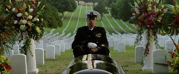 Movie still from “Act of Valor” (2012), directed by Scott Waugh – A man in a military uniform sitting in front of a cemetery; Wide shot, High angle