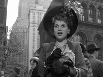 Movie still from “Adam's Rib” (1949), directed by George Cukor – A woman wearing a hat and gloves on a city street; Medium shot, Low angle