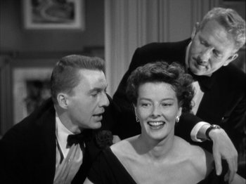 Movie still from “Adam's Rib” (1949), directed by George Cukor – A black and white photo of a man and a woman and another man; Medium shot, Over the shoulder angle