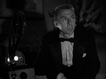 Movie still from “Adam's Rib” (1949), directed by George Cukor – A man in a tuxedo sitting in front of an old movie projector; Medium shot, Low angle