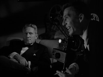 Movie still from “Adam's Rib” (1949), directed by George Cukor – A man in a suit and tie with a movie camera; Medium shot, Low angle