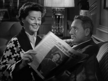 Movie still from “Adam's Rib” (1949), directed by George Cukor – An older man and a younger woman looking at a newspaper; Medium shot, Over the shoulder angle