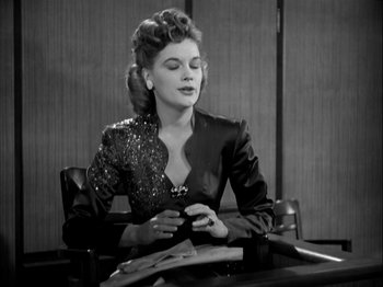 Movie still from “Adam's Rib” (1949), directed by George Cukor – A woman sitting at a table looking at her cell phone; Medium shot, Low angle