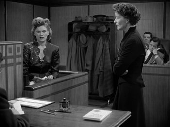 Movie still from “Adam's Rib” (1949), directed by George Cukor – Two women are talking in an old courtroom; Medium shot, Over the shoulder angle