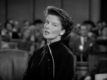 Movie still from “Adam's Rib” (1949), directed by George Cukor – An old black and white photo of a woman standing in front of an audience; Close Up shot, Low angle
