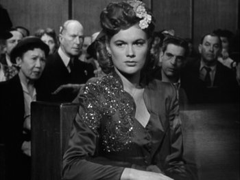 Movie still from “Adam's Rib” (1949), directed by George Cukor – A woman sitting in front of a group of people; Medium shot, Low angle