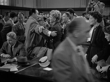 Movie still from “Adam's Rib” (1949), directed by George Cukor – A man and a woman shaking hands in a courtroom; Medium shot, Over the shoulder angle