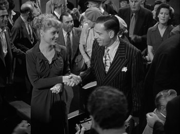 Movie still from “Adam's Rib” (1949), directed by George Cukor – A man and a woman shaking hands in front of a crowd of onlookers; Medium shot, Over the shoulder angle