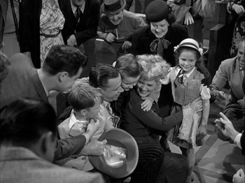 Movie still from “Adam's Rib” (1949), directed by George Cukor – A group of people gathered around a woman holding a bowl; Wide shot, High angle