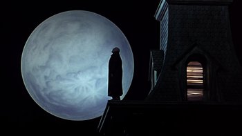 Movie still from “Addams Family Values” (1993), directed by Barry Sonnenfeld – A person standing in front of a large moon; Wide shot, Low angle