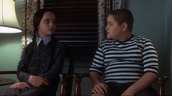 Movie still from “Addams Family Values” (1993), directed by Barry Sonnenfeld – Two people sitting on a chair in front of a window; Medium shot, Over the shoulder angle