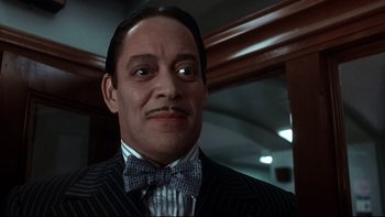 Movie still from “Addams Family Values” (1993), directed by Barry Sonnenfeld – A person wearing a suit and bow tie; Close Up shot, Low angle
