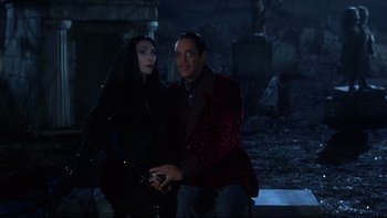Movie still from “Addams Family Values” (1993), directed by Barry Sonnenfeld – A man and a woman dressed as morticia and gomez addams; Medium shot, Over the shoulder angle