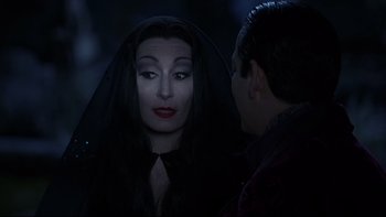 Movie still from “Addams Family Values” (1993), directed by Barry Sonnenfeld – A woman dressed as morticia addams is talking to a man; Close Up shot, Over the shoulder angle