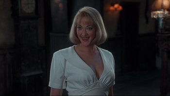 Movie still from “Addams Family Values” (1993), directed by Barry Sonnenfeld – A woman in a white dress smiling for the camera; Close Up shot, Over the shoulder angle