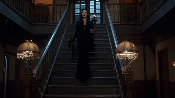 Movie still from “Addams Family Values” (1993), directed by Barry Sonnenfeld – A woman dressed in black walking down a set of stairs; Wide shot, High angle