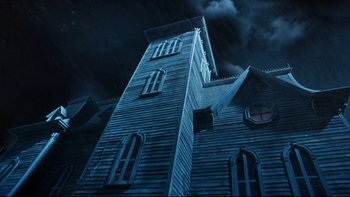 Movie still from “Addams Family Values” (1993), directed by Barry Sonnenfeld – A tall wooden building with a dark sky in the background; Extreme Wide shot, Low angle