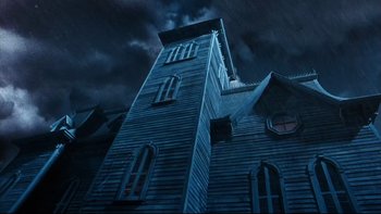 Movie still from “Addams Family Values” (1993), directed by Barry Sonnenfeld – A tall wooden building with a dark sky in the background; Extreme Wide shot, Low angle