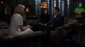 Movie still from “Addams Family Values” (1993), directed by Barry Sonnenfeld – Two women and a man sitting in a living room; Medium shot, High angle