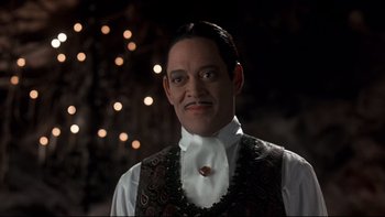 Movie still from “Addams Family Values” (1993), directed by Barry Sonnenfeld – A man in a white shirt and a brown vest; Close Up shot, Low angle