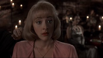 Movie still from “Addams Family Values” (1993), directed by Barry Sonnenfeld – A person with blonde hair wearing a pink shirt; Close Up shot, Over the shoulder angle